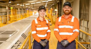 Two employees wearing orange hi vis inside Downer Maintenance Centre